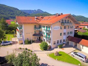 A two-story building with a red-tiled roof, a sign reading 'Salzburg Hof,' and a paved driveway.