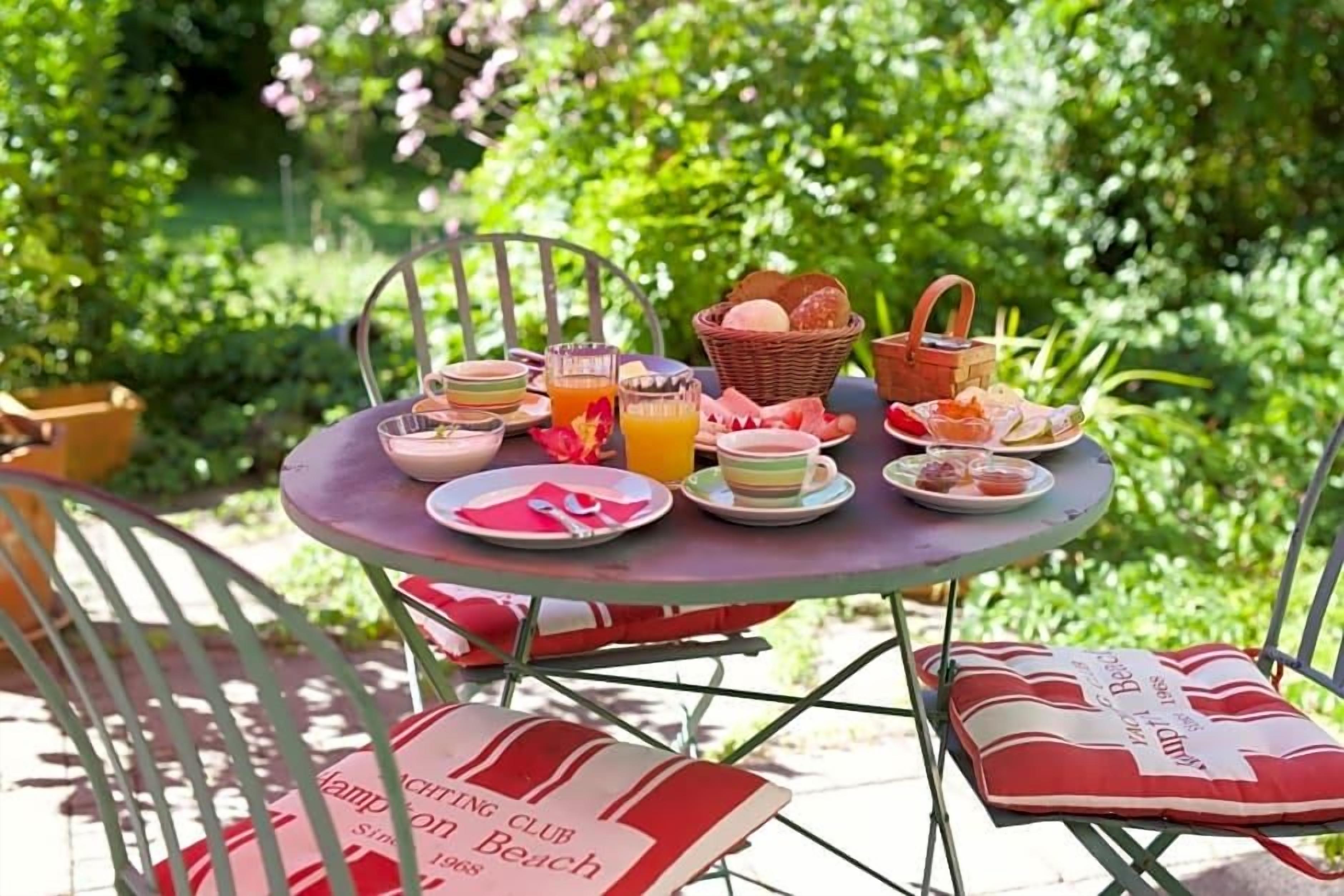 A round metal table with a picnic setup including plates, cups, and a basket.