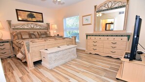 A bedroom with a bed, bedside tables, a bench, a dresser, a mirror, and a television. - Villa Sanibel 2B (Sanibel)