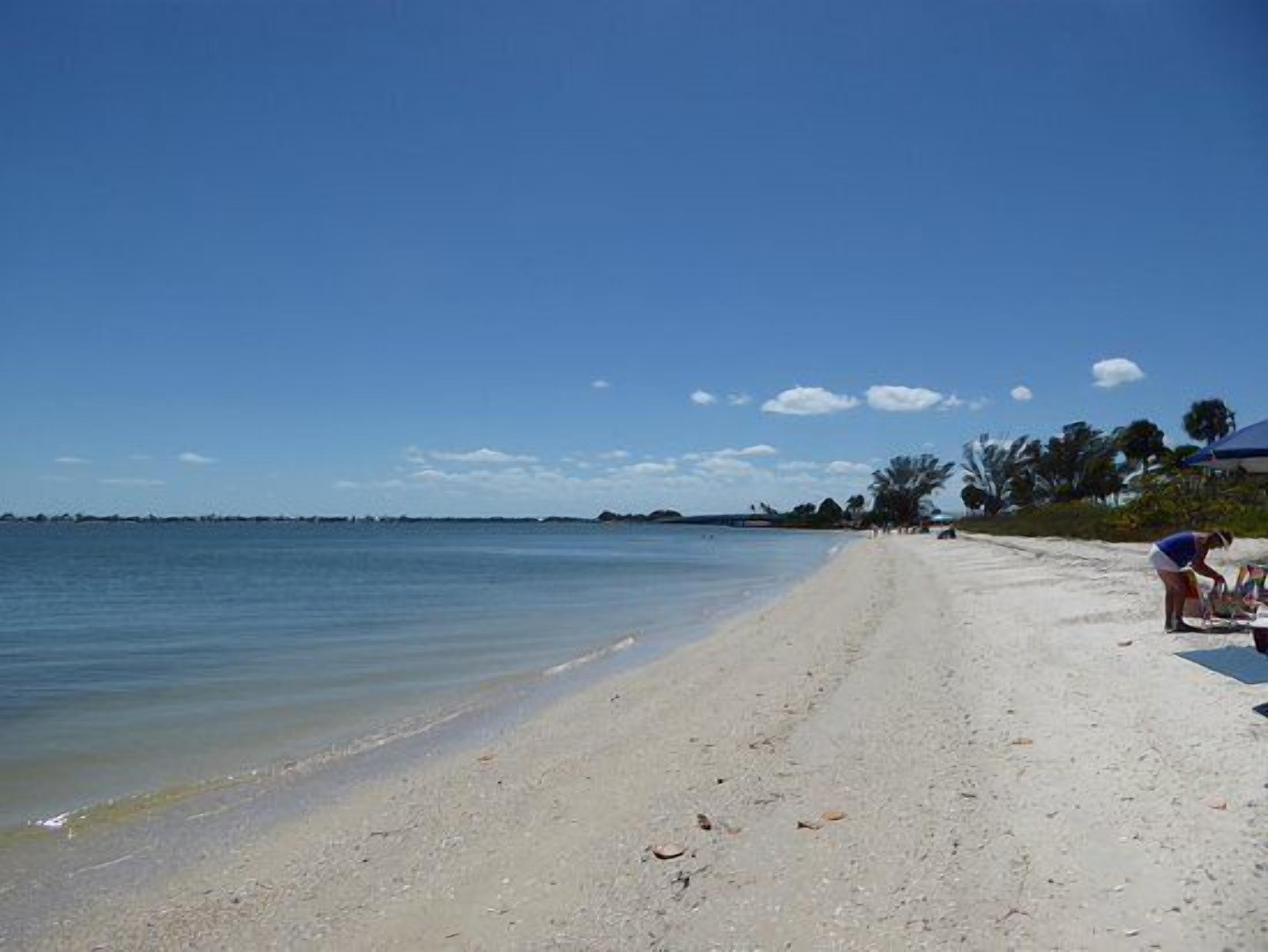 A beach with clear skies, calm water, and a few people.
