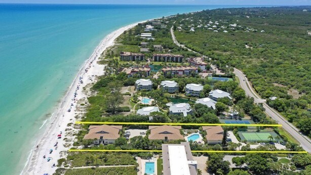 An aerial view of a coastal resort with beachfront villas, a swimming pool, and a road running parallel to the beach. - Villa Sanibel 2B (Sanibel)