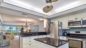Une cuisine moderne avec des meubles blancs, des appareils électroménagers en acier inoxydable et un îlot central.