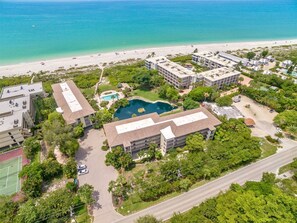 An aerial view of a coastal hotel with multiple buildings, a swimming pool, and a beach. - Sand Pointe 212 (Sanibel)