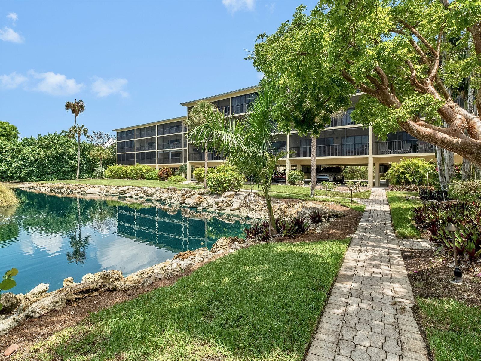 A modern building with a swimming pool, surrounded by well-maintained greenery and a paved walkway.