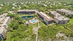 Vue aérienne d’un complexe hôtelier comprenant plusieurs bâtiments, une piscine et une végétation luxuriante.