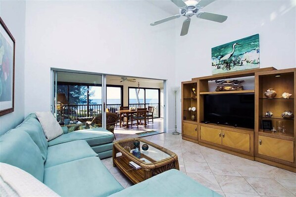 A living room with a sofa, TV stand, and a balcony with a view.