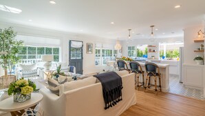 A spacious living room with a sofa, chairs, and a dining area with a bar. - Casa Miramar - Coastal Farmhouse Chic Getaway (Santa Barbara)