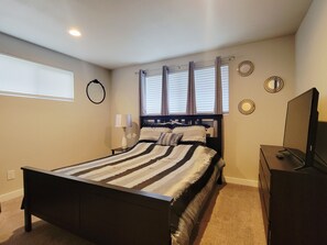 A bedroom with a bed, a dresser, a TV, a window with blinds, and a wall-mounted mirror. - Spacious newly remodeled 3br 2ba in heart of the Seattle (Seattle)