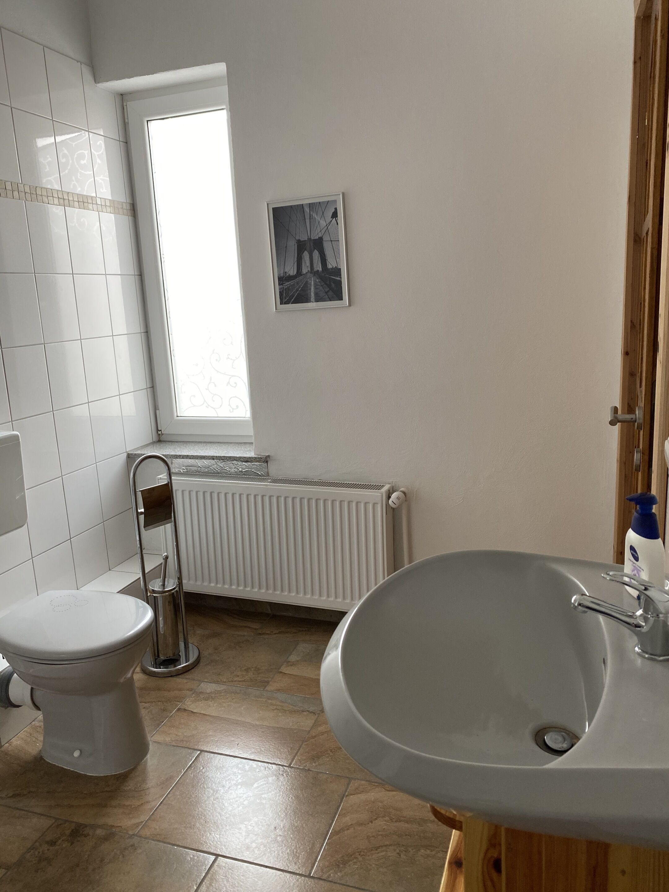 Un bagno con il water, un lavandino, un termosifone e una finestra.