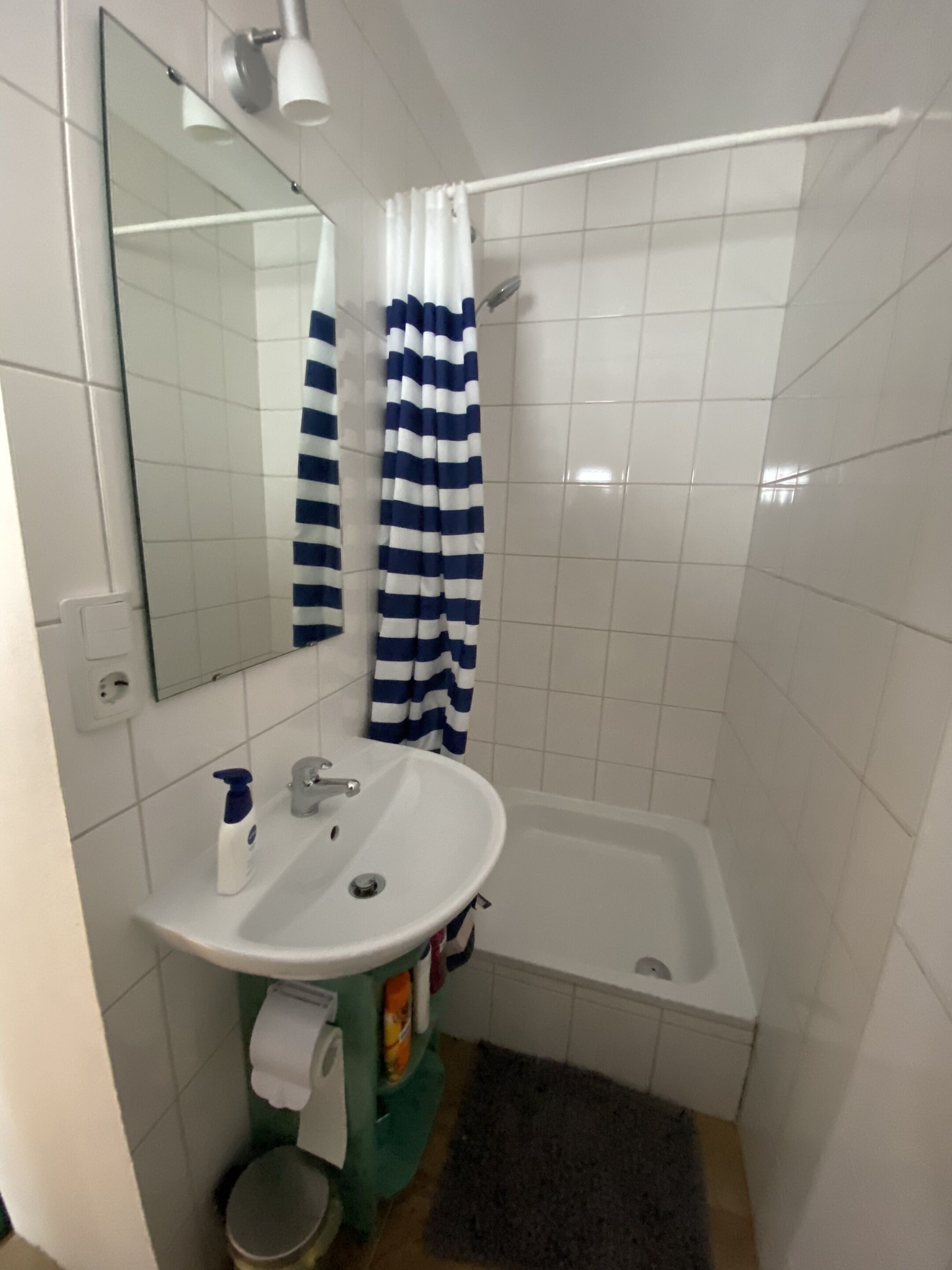 Ett badrum med ett vitt handfat, en spegel, en duschdraperi och ett badkar.