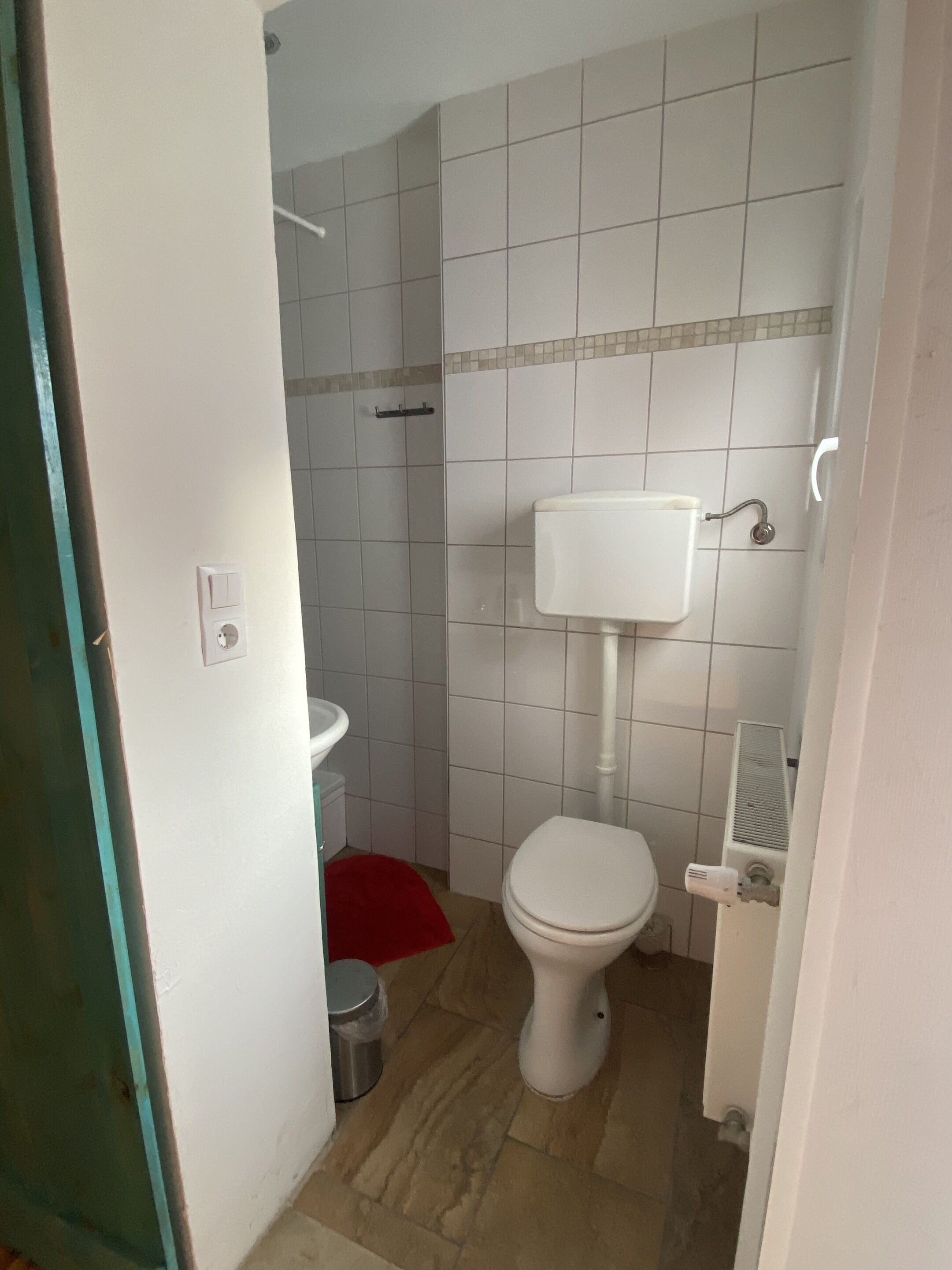 Een kleine badkamer met toilet, wastafel en douche.