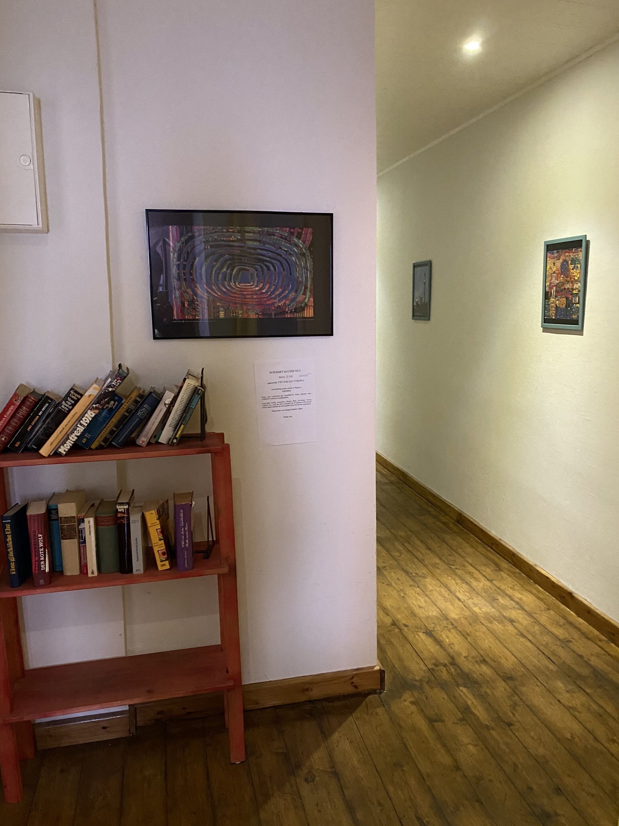 A hallway with bookshelves, framed artworks, and a sign indicating internet access.