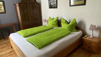 Una camera da letto con un letto in legno, cuscini verdi, un comodino in legno, una lampada e due quadri appesi al muro.