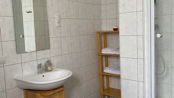 A bathroom with a white sink, mirror, and tiled walls.