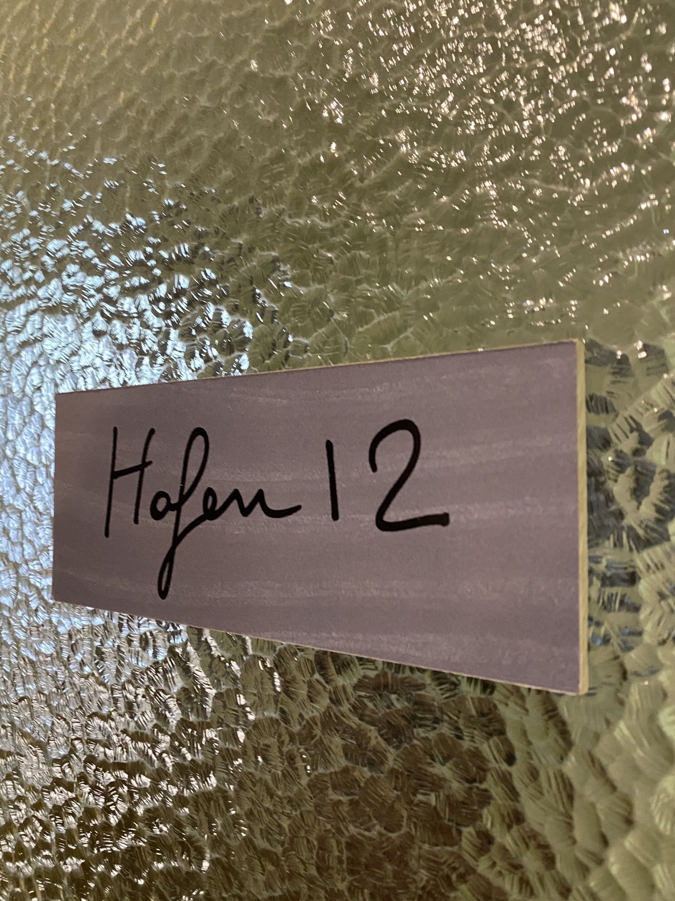 Un cartel con el texto 'Hafen 12' sobre una superficie texturizada.