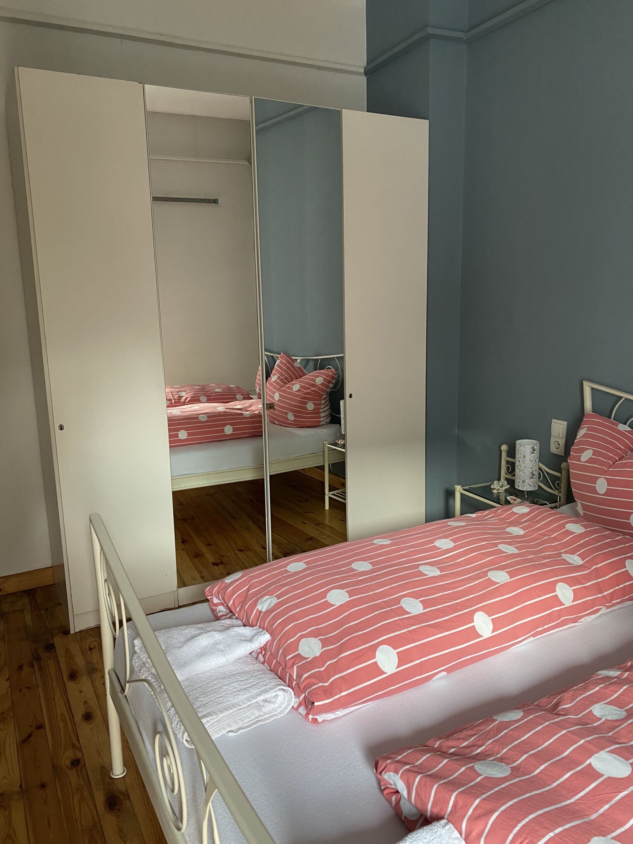 A bedroom with a bunk bed, a wardrobe, and a bedside table with a lamp.