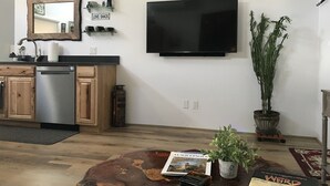 Una cocina moderna con lavavajillas incorporado, un televisor de pantalla plana grande y una cafetera.