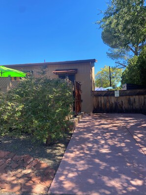 A building with a wooden fence, a paved walkway, and a sign indicating guest parking.