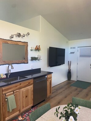 Eine moderne Küche mit Holzschränken, einem Geschirrspüler, einer Spüle und einem flachbildschirmfernseher an der Wand.