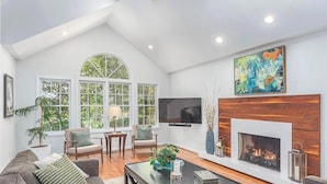 A living room with a fireplace, a television, and a large window.
