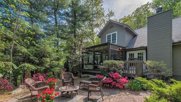 A house with a covered patio, outdoor furniture, and a garden with flowering plants.