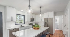 A modern kitchen with white cabinetry, stainless steel appliances, a central island, and pendant lighting. - Luxury Home off Town Mountain Rd / 2mi to dt AVL (Asheville)