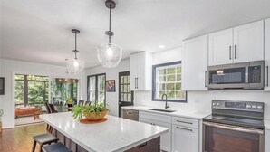 A modern kitchen with white cabinetry, stainless steel appliances, and a large island with seating.