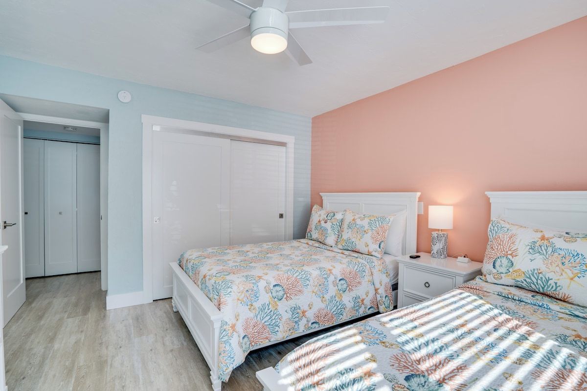 A bedroom with a bed, bedside table, lamp, and a ceiling fan.
