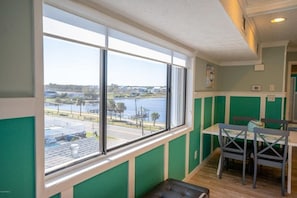 Enjoy a serene view of the water and distant landscape from the large window in this room, which features a dining area with a table and chairs, and a comfortable bench.