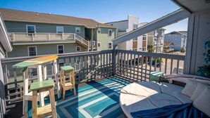 A balcony with a blue and white patterned floor, wooden furniture, and a white cushioned seating area. - Pool! First row from beach front with 2 Private Balconies (Carolina Beach)