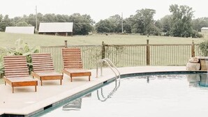 A swimming pool with wooden lounge chairs and a metal ladder. - Quiet Escape from the City (Fitzpatrick)
