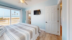A bedroom with a bed, a TV mounted on the wall, and a door leading to a bathroom.