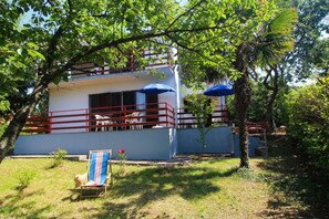 A two-story building with a balcony, a chair, and a blue umbrella. - Brankica Island Apartments (Malinska-Dubasnica)