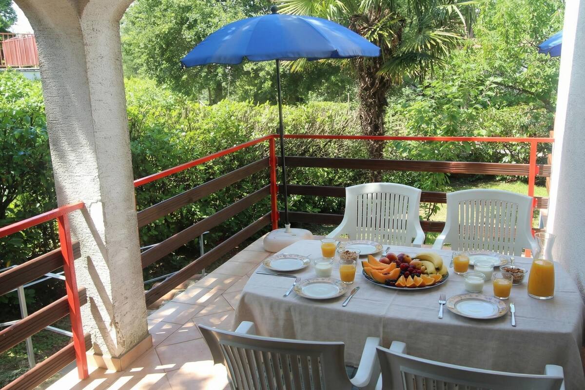 A table set outdoors with a tablecloth, plates, cutlery, and a fruit platter.