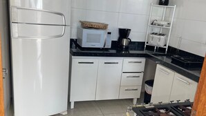 Una cocina compacta equipada con refrigerador, microondas, estufa y cafetera.