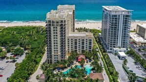 Un hotel di grandi dimensioni con piscina e vista sulla spiaggia, immerso nel verde e con area parcheggio.