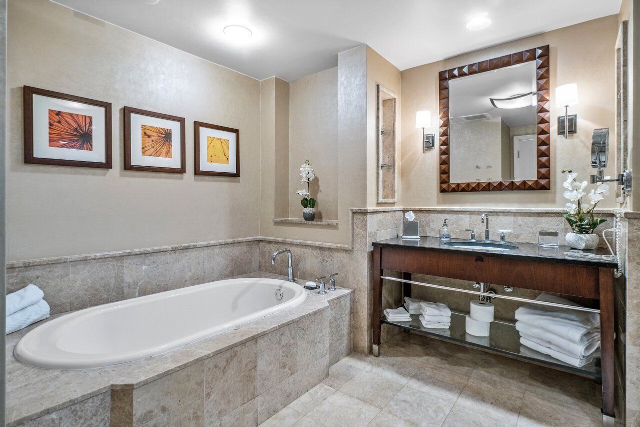 A modern bathroom with a freestanding bathtub, a vanity with a mirror, and framed artwork on the wall.