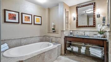 A modern bathroom with a freestanding bathtub, a vanity with a mirror, and framed artwork on the wall.