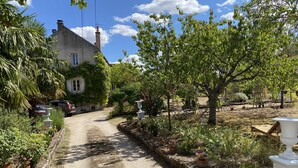 Ein Feldweg führt zu einem Haus mit Garten und Außenmöbeln.