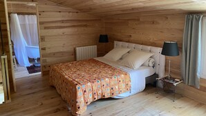 Ein Schlafzimmer mit Holzwandverkleidung, einem Bett, zwei Nachttischlampen, einem Heizkörper und einem kleinen Tisch mit Lampe.