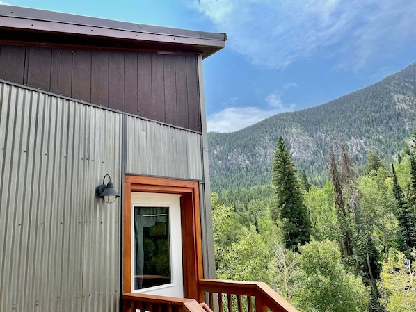 A building with a wooden deck and a door, surrounded by forest and mountains. - Dog Friendly•Close to Monarch•King Beds (Salida)