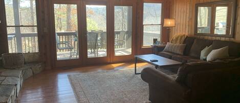 A wooden interior with a sofa, coffee table, and a view through large glass doors to an outdoor deck.