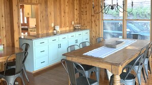 Un interior de madera con una mesa de comedor, sillas y una zona de cocina.