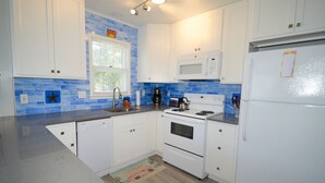 A kitchen with white cabinets, a microwave, a stove, and a refrigerator. - Beach home nestled between the beach and the bay (eastside) (Bethany Beach)