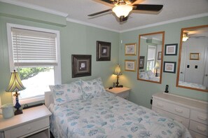 A bedroom with a bed, a nightstand, a dresser, a ceiling fan, a window with blinds, and framed pictures on the wall. - 472 Pool,HotTub,Elevator,OceanViews,DogFriendly (Nags Head)