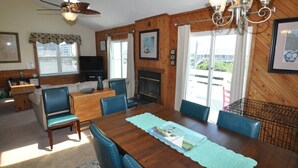 A dining area with a wooden table, blue chairs, a fireplace, and a view of the outdoors.