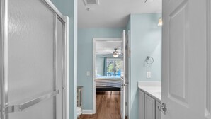 Un pasillo con suelo de madera que conduce a un dormitorio con cama y ventana.