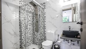 A modern bathroom with a glass-enclosed shower, a white toilet, and a black sink with a marble countertop. - Terra di Meteora Suites #3 (Kalampaka)