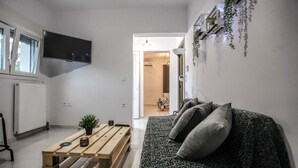 A modern living room with a sofa, a wooden coffee table, and a TV mounted on the wall. - Terra di Meteora Suites #3 (Kalampaka)