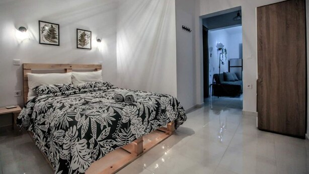 A bedroom with a bed, bedside tables, and a wooden wardrobe. - Terra di Meteora Suites #3 (Kalampaka)